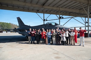 Civilians pose for a group photo in front of a fighter jet