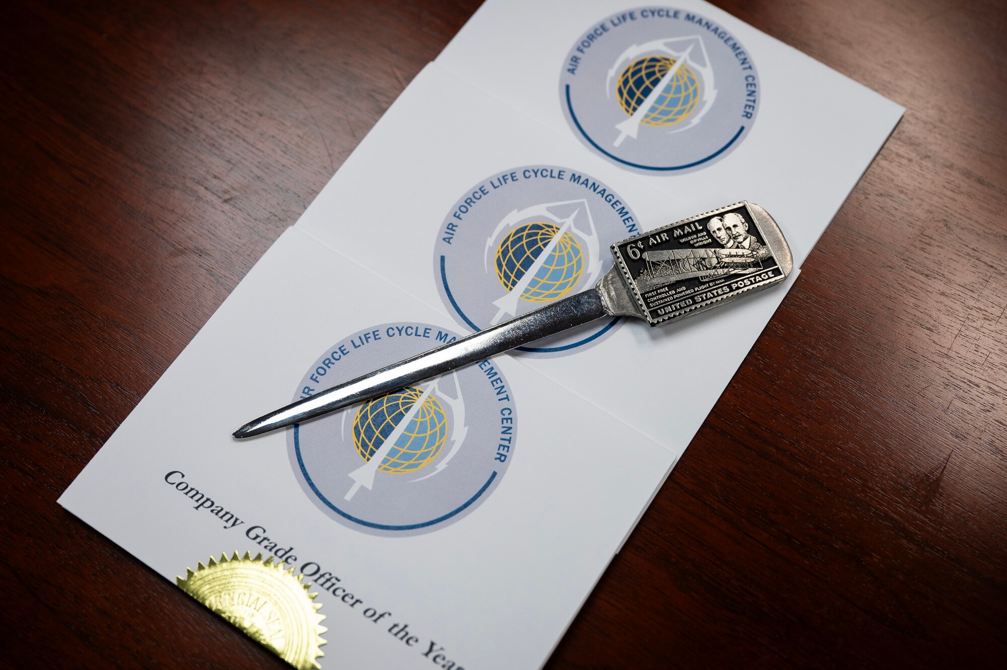 Pile of envelopes and an opener sit on wood table.