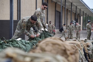 Two men in U.S. Air Force uniforms place bags in a line.