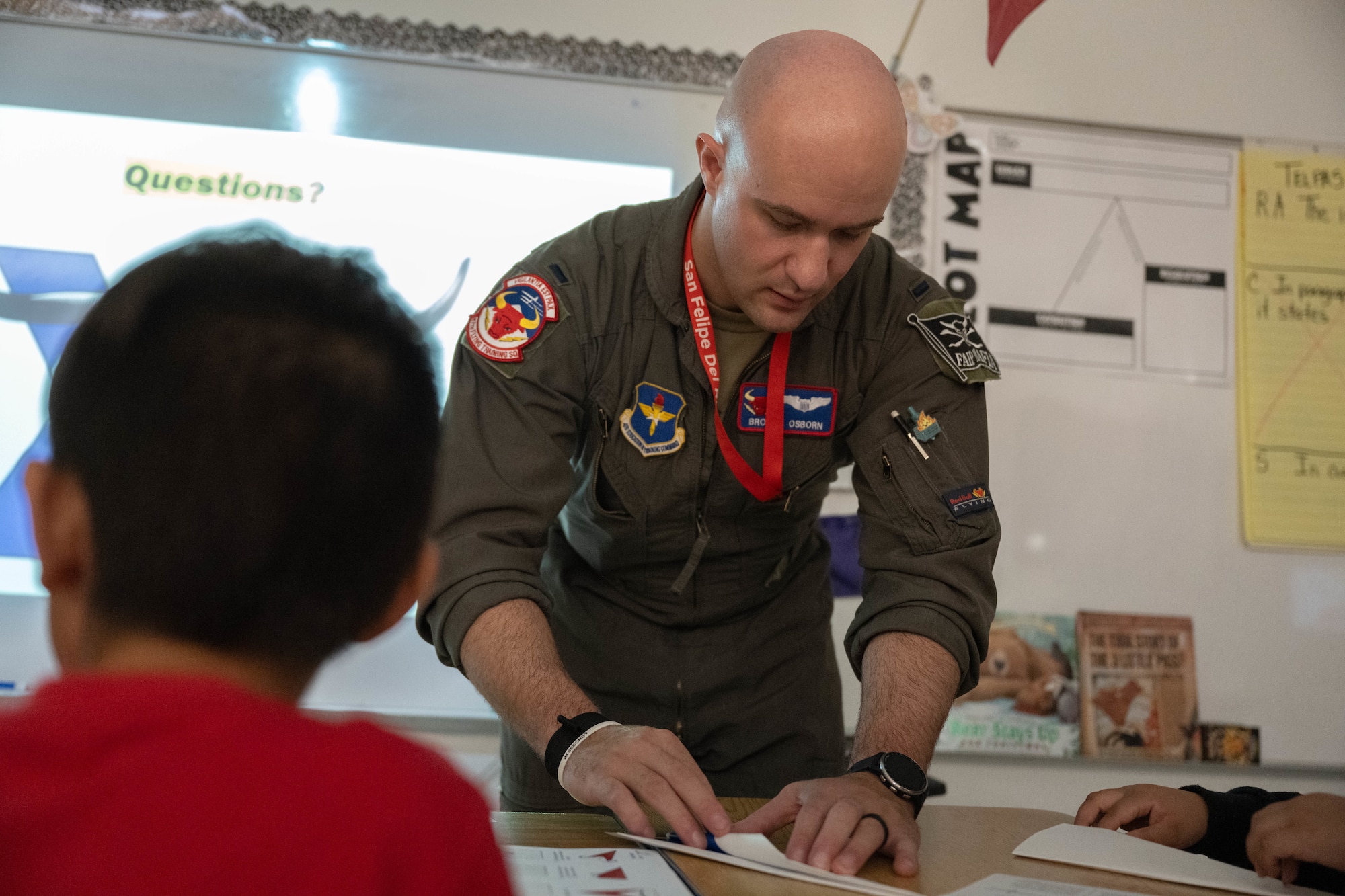 U.S. Air Force 1st Lt. Alex Osborn, 87th Flying Training Squadron T-38 instructor pilot, helps a student make a paper airplane at Lamar Elementary School in Del Rio, Texas, Feb. 19, 2026. Osborn helped students prepare for a paper airplane contest during the Laughlin Buddies afterschool program. (U.S. Air Force photo by Airman 1st Class Darryl Keith)