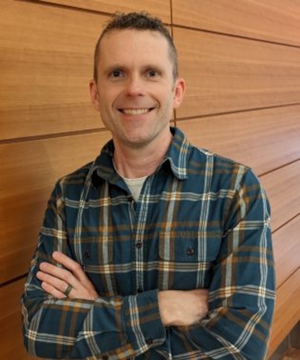 Air Force Capt Finn Kuusisto, lead AI engineer, Air Force Accelerator casually poses for a phot in a blue and yellow flannel shirt