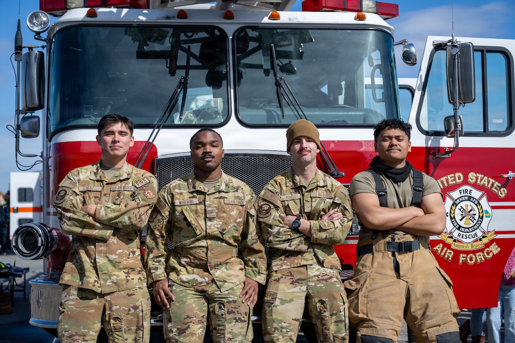 U.S. Air Force Airmen, 23d Civil Engineer Squadron firefighters, pose for a portrait during the Saluting Our Aviation Roots static display at Moody Air Force Base, Georgia, Feb. 24, 2026. The firefighters display specialized equipment, allowing attendees to hold the gear and experience its weight. (U.S. Air Force photo by Airman 1st Class Noah Noonan)
