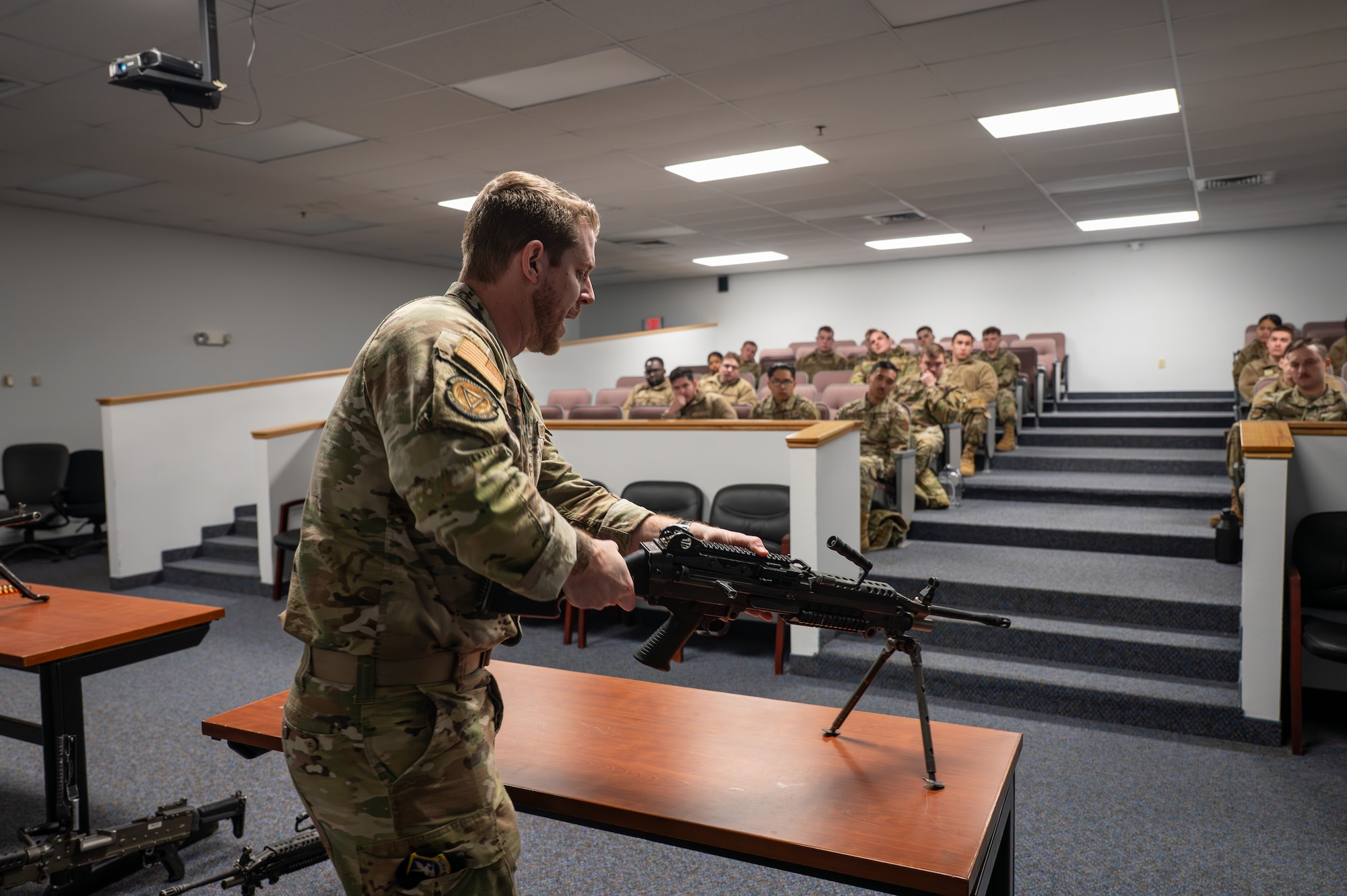 Uniformed man teaches a class of uniformed personnel.