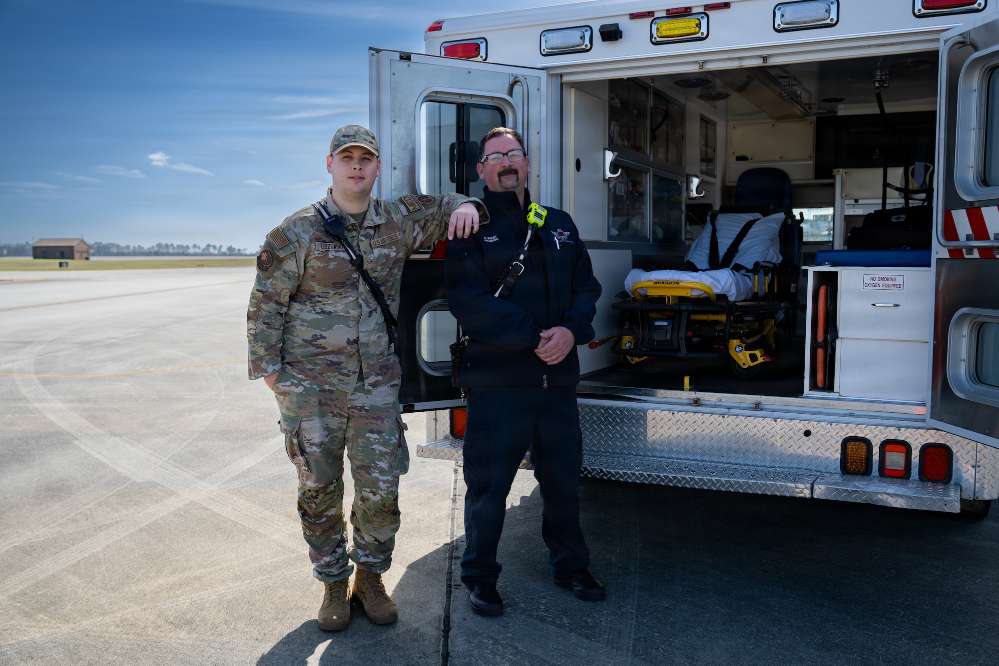 U.S. Air Force Senior Airman Nathan Liszewski, 23d Medical Group aerospace medical service technician, and a local paramedic pose for a portrait outside an ambulance during the Saluting Our Aviation Roots static display at Moody Air Force Base, Georgia, Feb. 25, 2026. Attendees had the opportunity to learn about emergency response capabilities and the equipment used to keep the base safe. (U.S. Air Force photo by Airman 1st Class Rachel Howell)