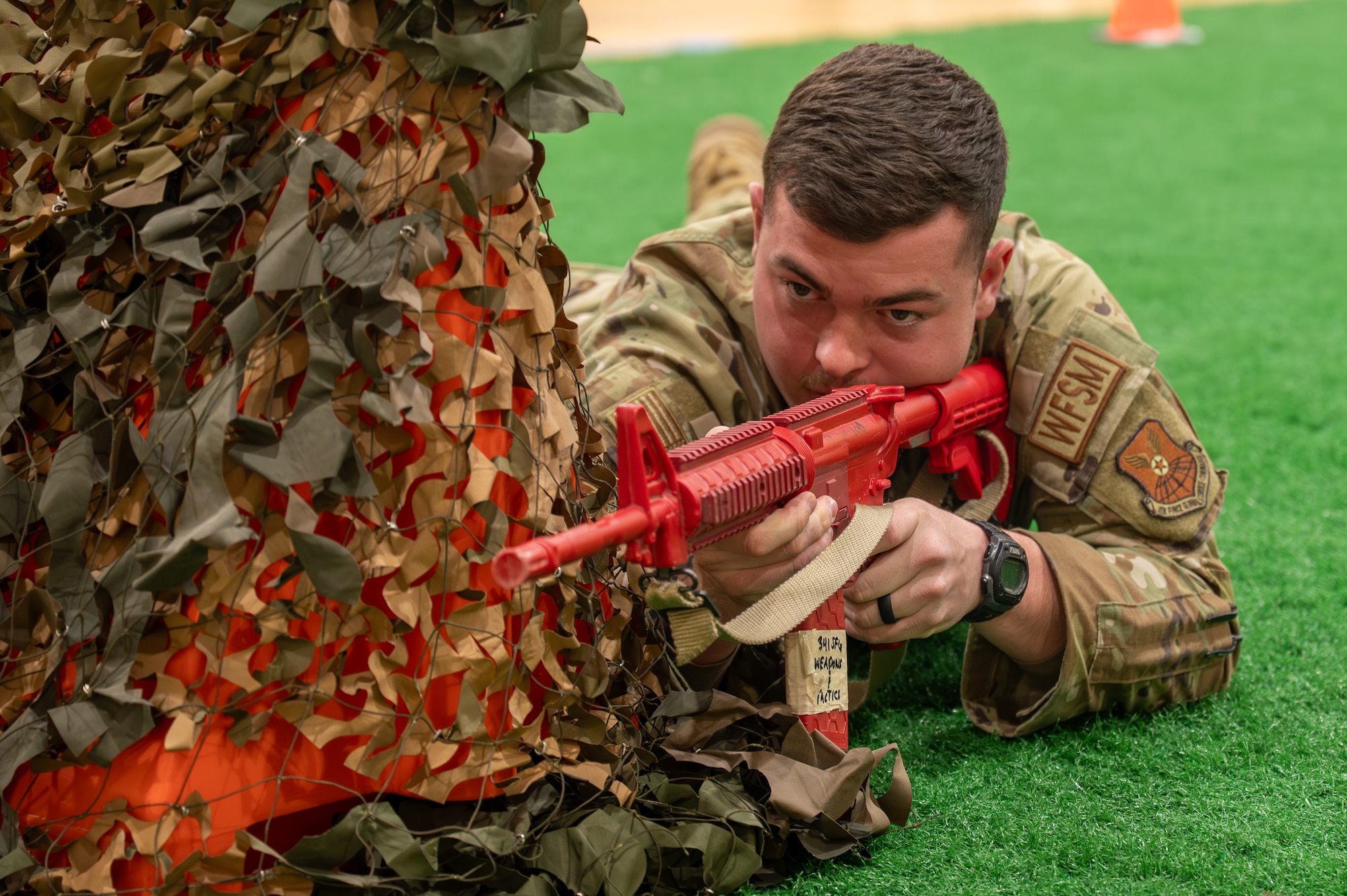 Uniformed man aims a trainer weapon.