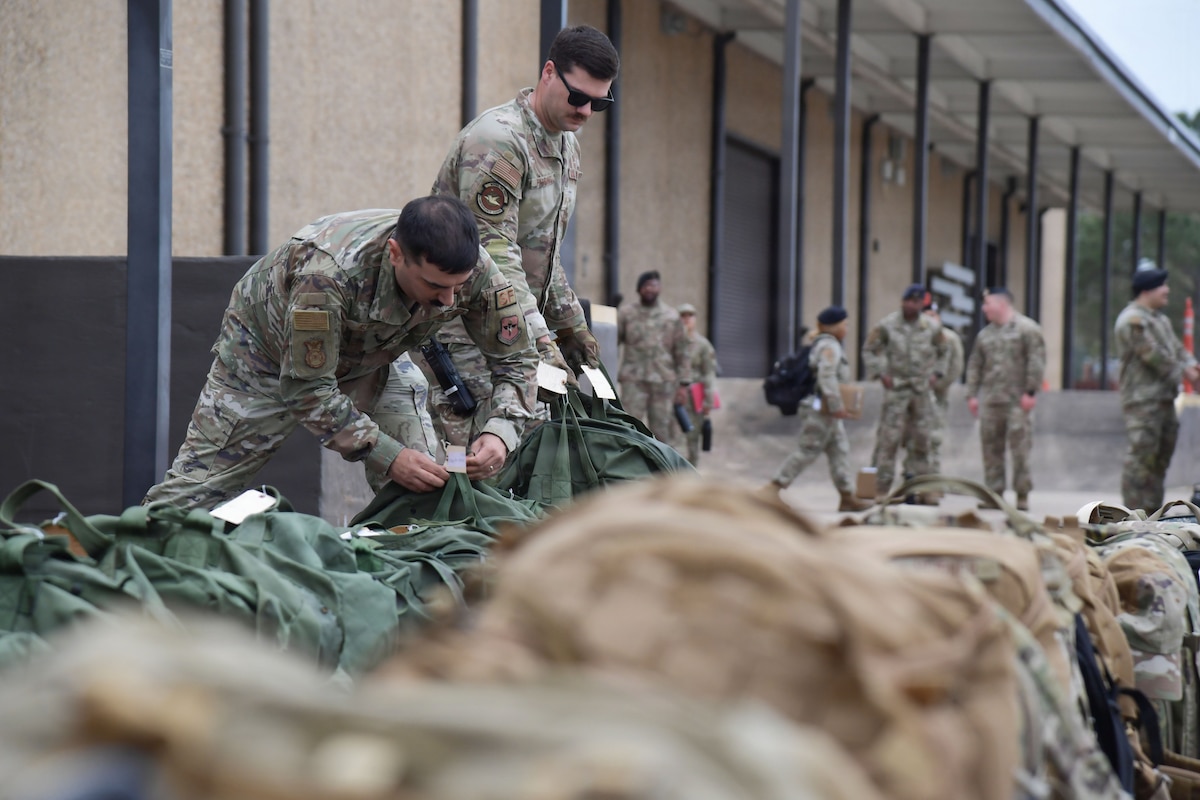 Two men in U.S. Air Force uniforms place bags in a line.