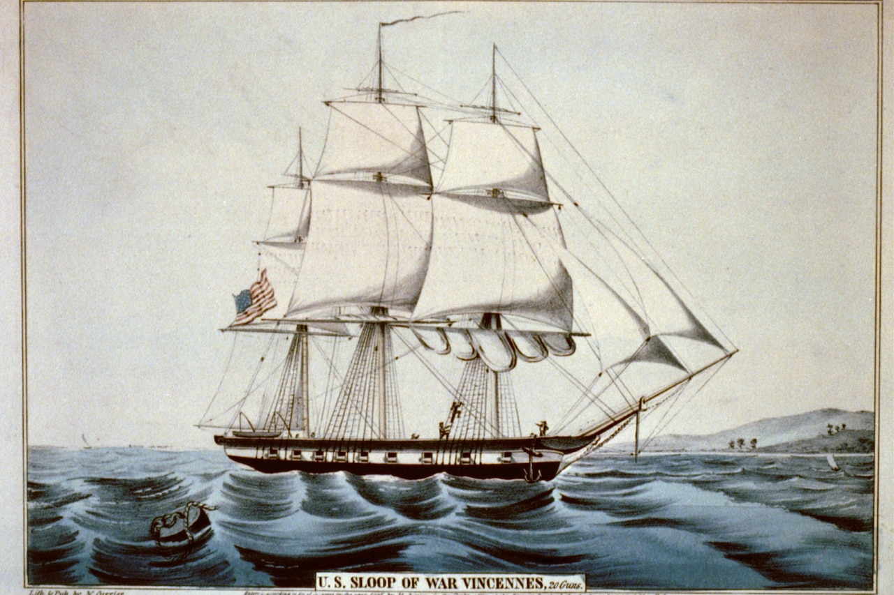 A large sailing ship, flying an American flag, floats at sea with mountains in the distance.