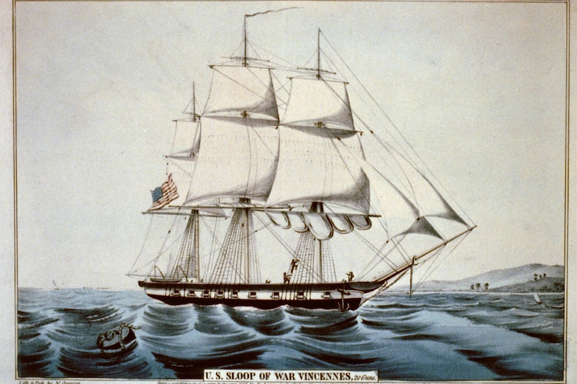 A large sailing ship, flying an American flag, floats at sea with mountains in the distance.