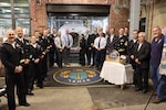 GROTON, Conn. (Nov. 6, 2025) Past and present members of Naval Submarine Medical Research Laboratory (NSMRL) gather to cut a ceremonial ribbon following the certification ceremony for the Genesis Chamber. NSMRL, part of Navy Medicine Research & Development and based out of Groton, Connecticut, sustains the readiness and superiority of U.S. undersea warfighters through innovative health and performance research and works to lead the world in delivering science solutions to ensure undersea warrior dominance. (U.S. Navy photo by Emily Swedlund /Released)