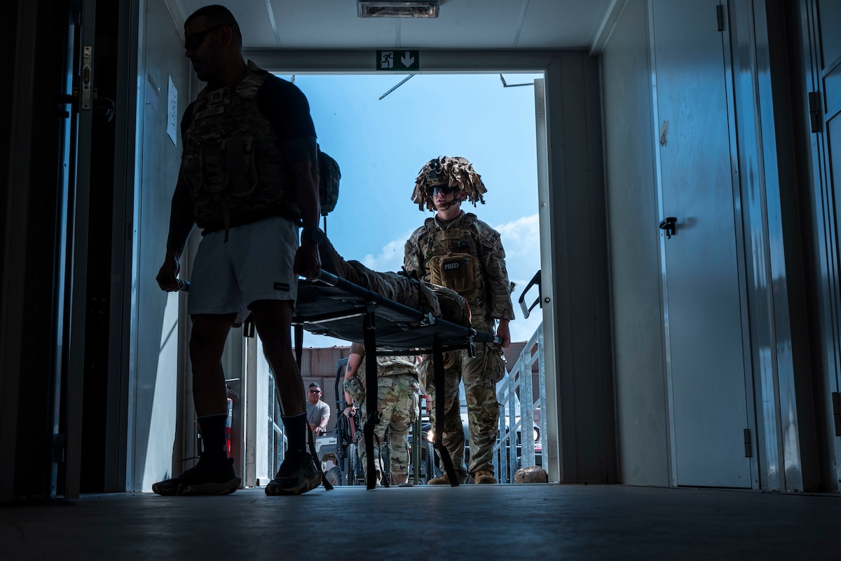 Two soldiers bring a person into a building on a gurney.