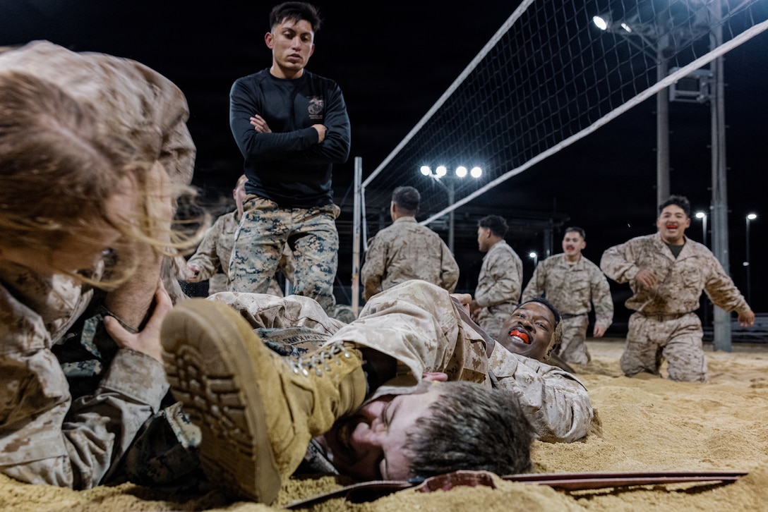 U.S. Marines Corps Cpl. Pablo Almaraz, an aviation ordinance system technician with Marine Aircraft Group 12, 1st Marine Aircraft Wing, supervises a ground fighting event during a Marine Corps Martial Arts Program culminating event at Marine Corps Air Station Iwakuni, Japan, Dec. 13, 2025. Marines from MCAS Iwakuni conducted a five-hour culminating event that challenged students in mental resilience and warrior discipline through lethal close quarters combat training and physical conditioning. (U.S. Marine Corps photo by Cpl. Sarah M. Grawcock)