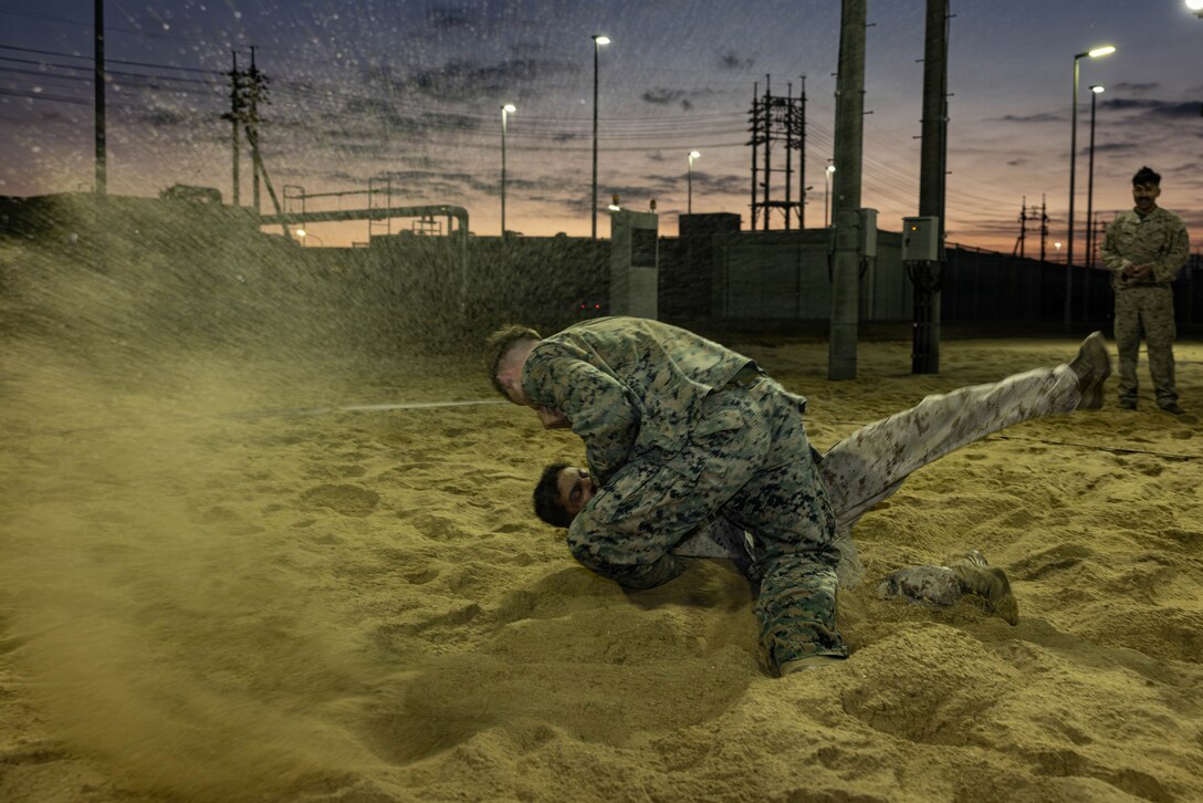U.S. Marine Corps Lance Cpl. Tyler Hawkins, top, a military police officer with Headquarters and Headquarters Squadron (HHS), Marine Corps Air Station Iwakuni, and a native of De Kalb, Texas, executes a hip throw during a Marine Corps Martial Arts Program culminating event at MCAS Iwakuni, Japan, Dec. 13, 2025. Marines from Iwakuni conducted a five-hour culminating event that challenged students in mental resilience and warrior discipline through lethal close quarters combat training and physical conditioning. (U.S. Marine Corps photo by Lance Cpl. Ella Cadby)