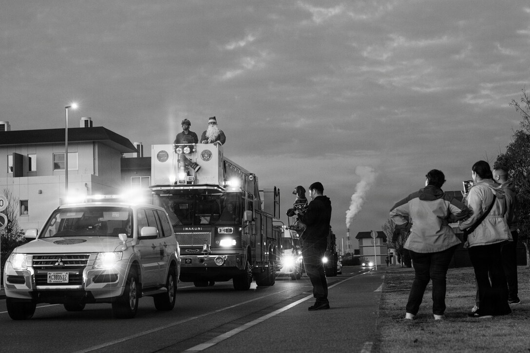 The community of Marine Corps Air Station Iwakuni watch a Christmas Parade at MCAS Iwakuni, Japan, Dec. 19, 2025. The Christmas Parade is an annual event held by MCAS Iwakuni Aircraft Rescue and Firefighting to help build community moral and holiday cheer before the year comes to an end. (U.S. Marine Corps photo illustration by Cpl. Sarah M. Grawcock) 

This image was created in color and changed to black-and-white in lightroom.
