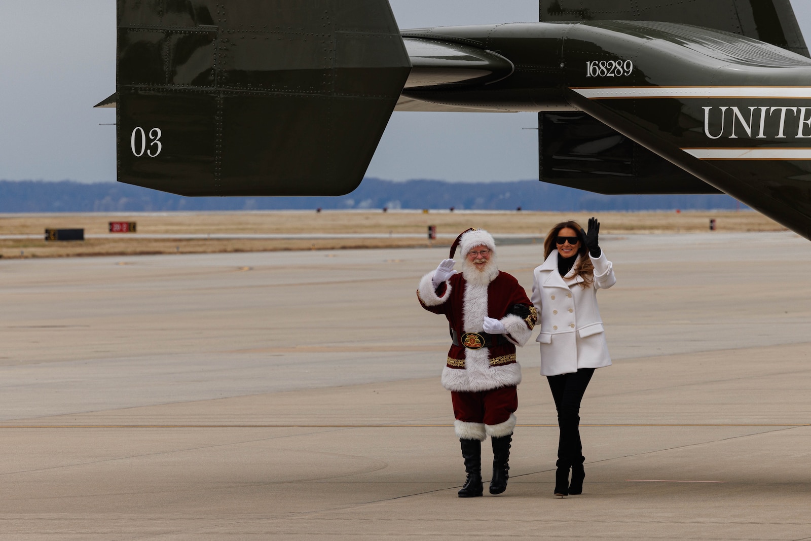 Santa Claus and First Lady Melania Trump wave to children waiting to greet them on the runway of Marine Corps Air Facility on Marine Corps Base Quantico, Virginia, Dec. 8, 2025. Mrs. Trump told a story to children in attendance, helped sort toys for Toys for Tots, and helped them make Christmas cards. (U.S. Marine Corps photo by Lance Cpl. David Brandes)