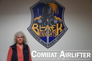 Woman poses in front of wall.