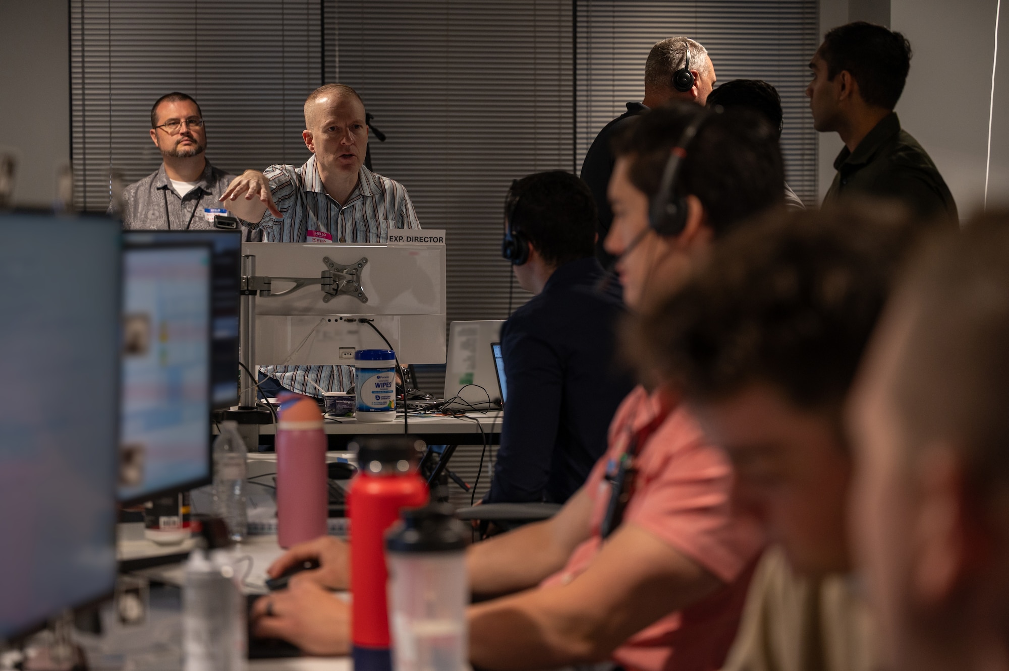 people sit and stand around computer stations