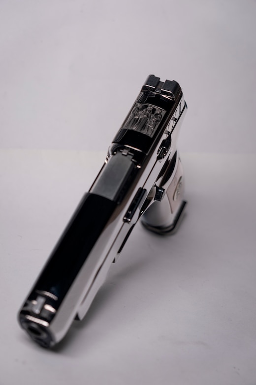 Image from above of a shiny pistol with wood on the stock.