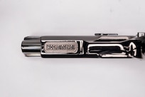 Image of the underside of the barrel of a shiny pistol with the word SILENCE inscribed on it.