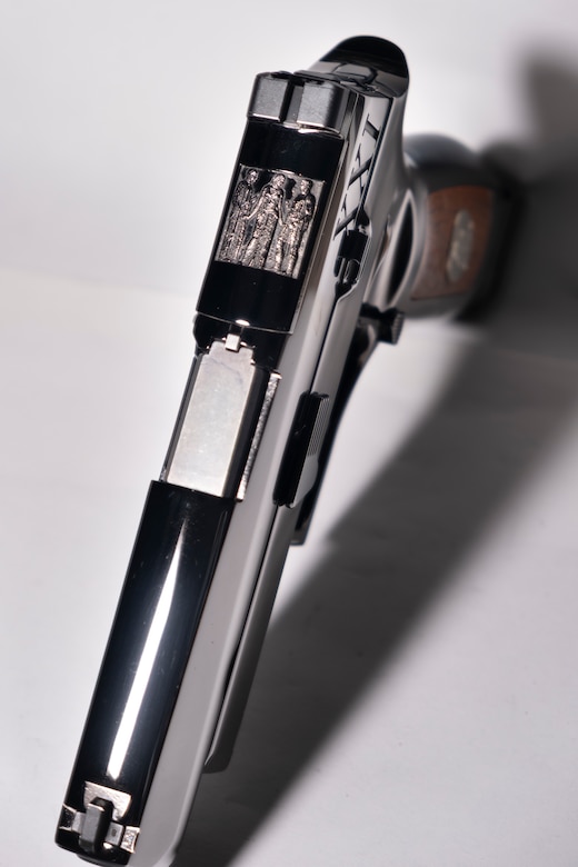 Image from above of a shiny pistol with wood on the stock.