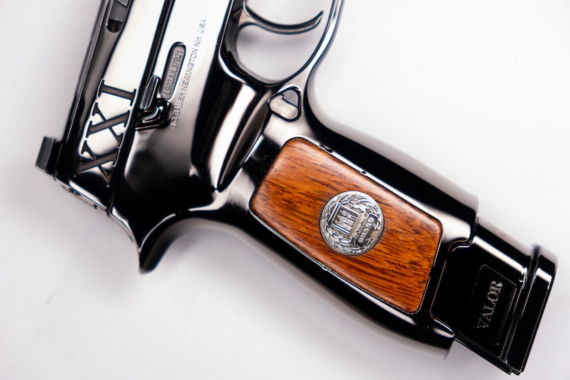 Image of a shiny pistol with wood on the stock and the letters XXI inscribed on it near the hammer.