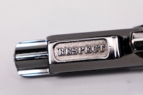 Close-up shot of the silver barrel of a pistol that has the word RESPECT inscribed on it.
