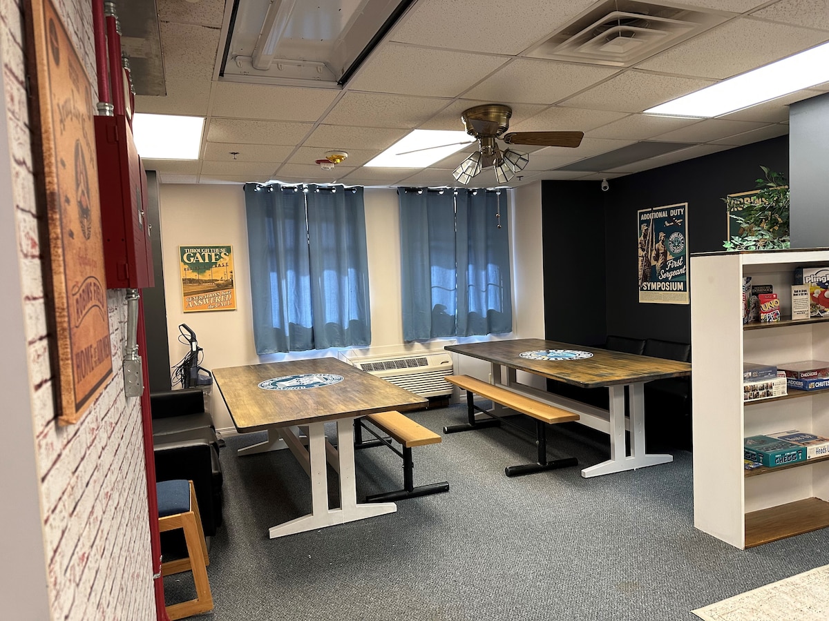 a completed room shows two tables with bench seating and a bookcase with games