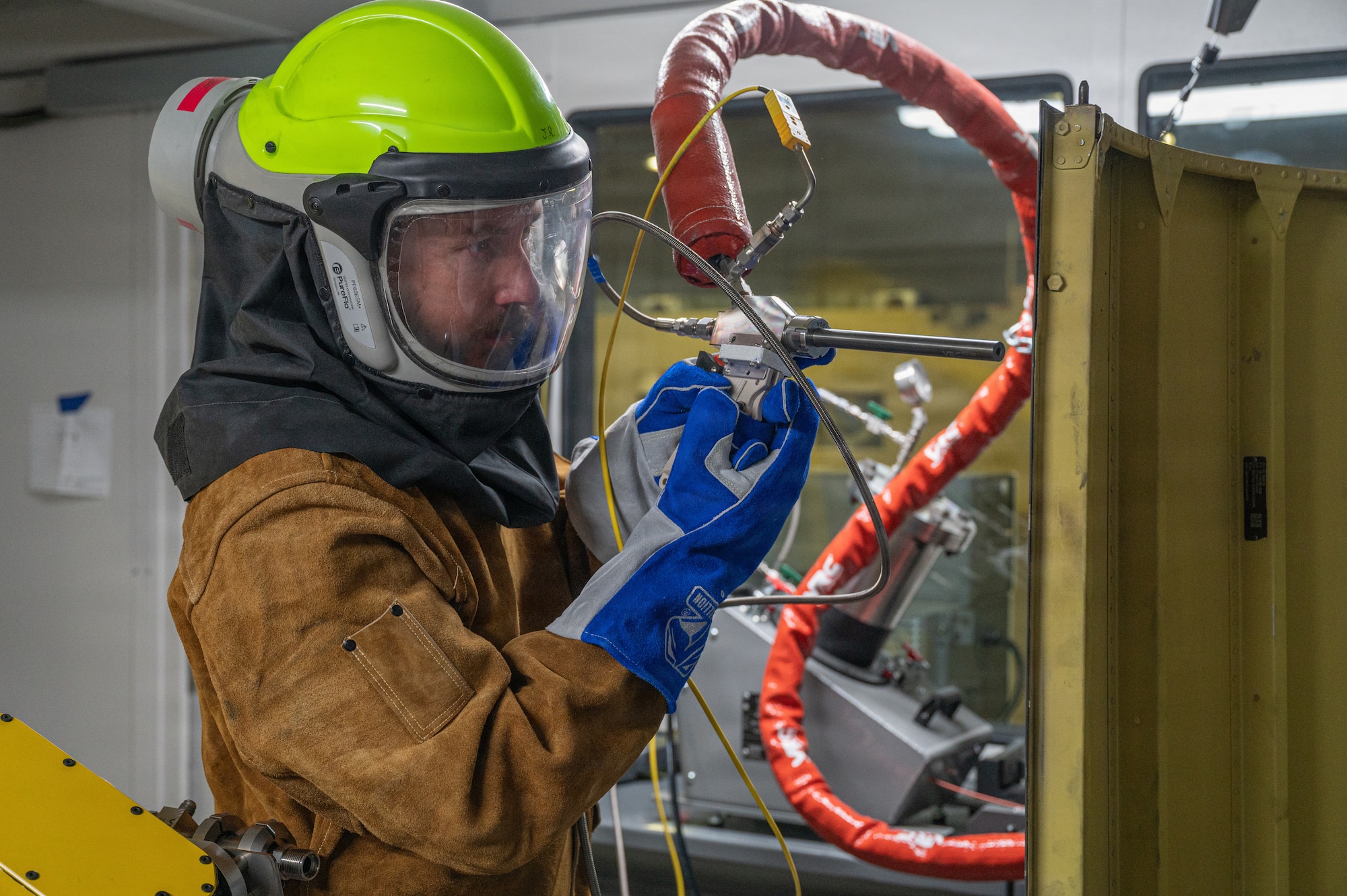 A cold spray technician operates a spray nozzle for cold spray application on a B-52H Stratofortress panel.