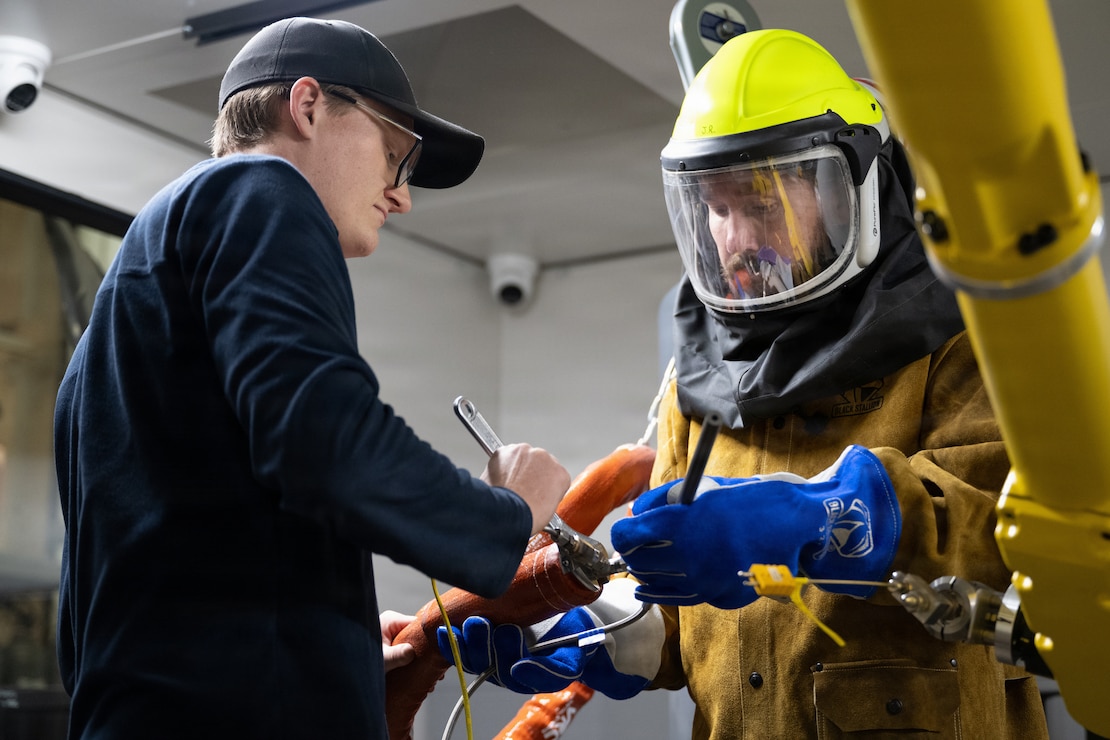 engineer changes the nozzle on a cold spray robot arm.
