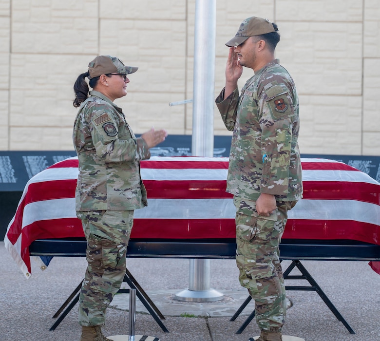 U.S. Air Force Lt. Col. Maria Berardo (left), 56th Force Support Squadron commander, and Senior Airman Ezekiel Gonzales-McCallum (right), 56th Fighter Wing honor guardsman, returns a salute after presenting a challenge coin for exemplary performance during a ceremony, Dec. 2, 2025, at Luke Air Force Base, Arizona.