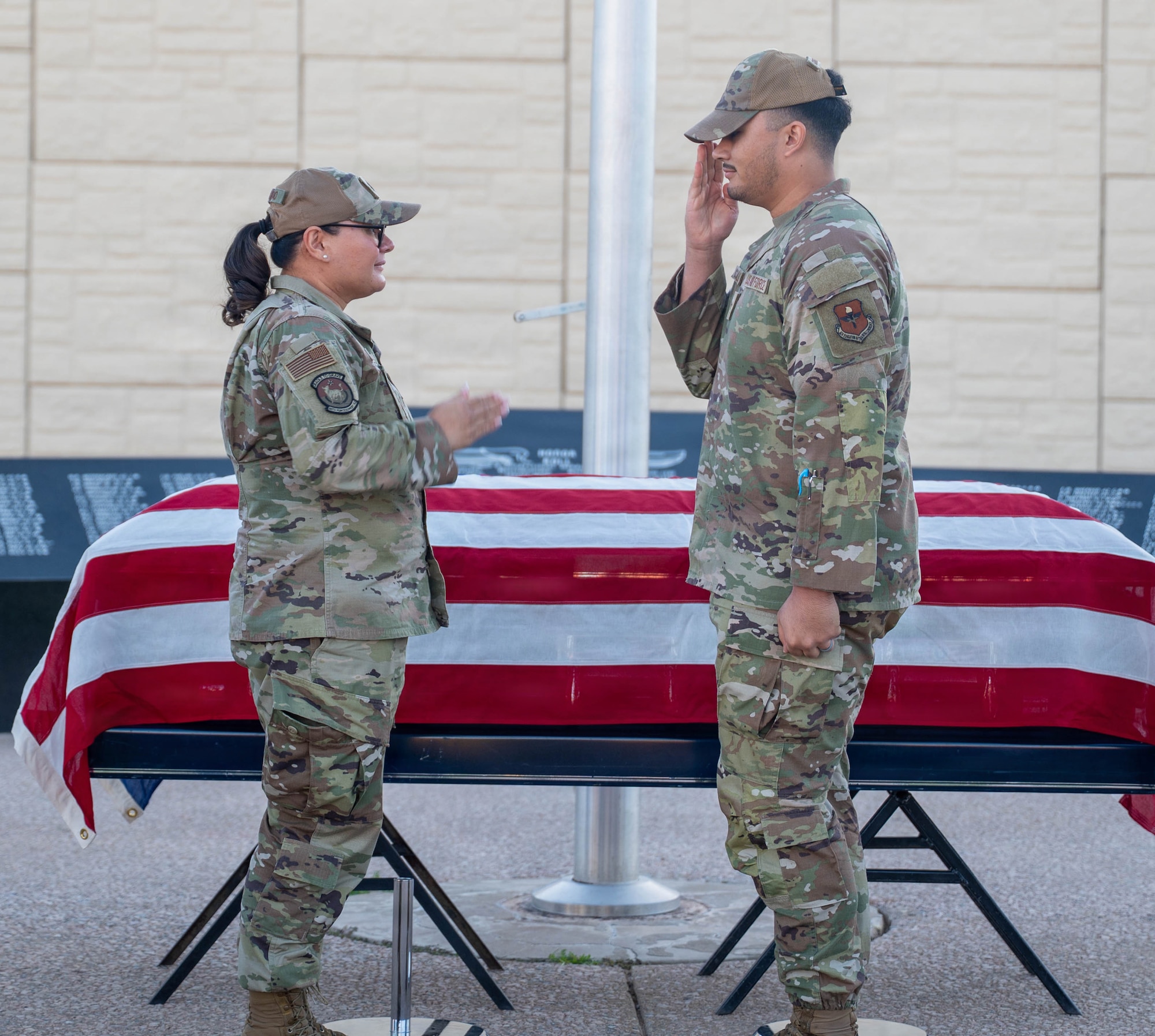U.S. Air Force Lt. Col. Maria Berardo (left), 56th Force Support Squadron commander, and Senior Airman Ezekiel Gonzales-McCallum (right), 56th Fighter Wing honor guardsman, returns a salute after presenting a challenge coin for exemplary performance during a ceremony, Dec. 2, 2025, at Luke Air Force Base, Arizona.