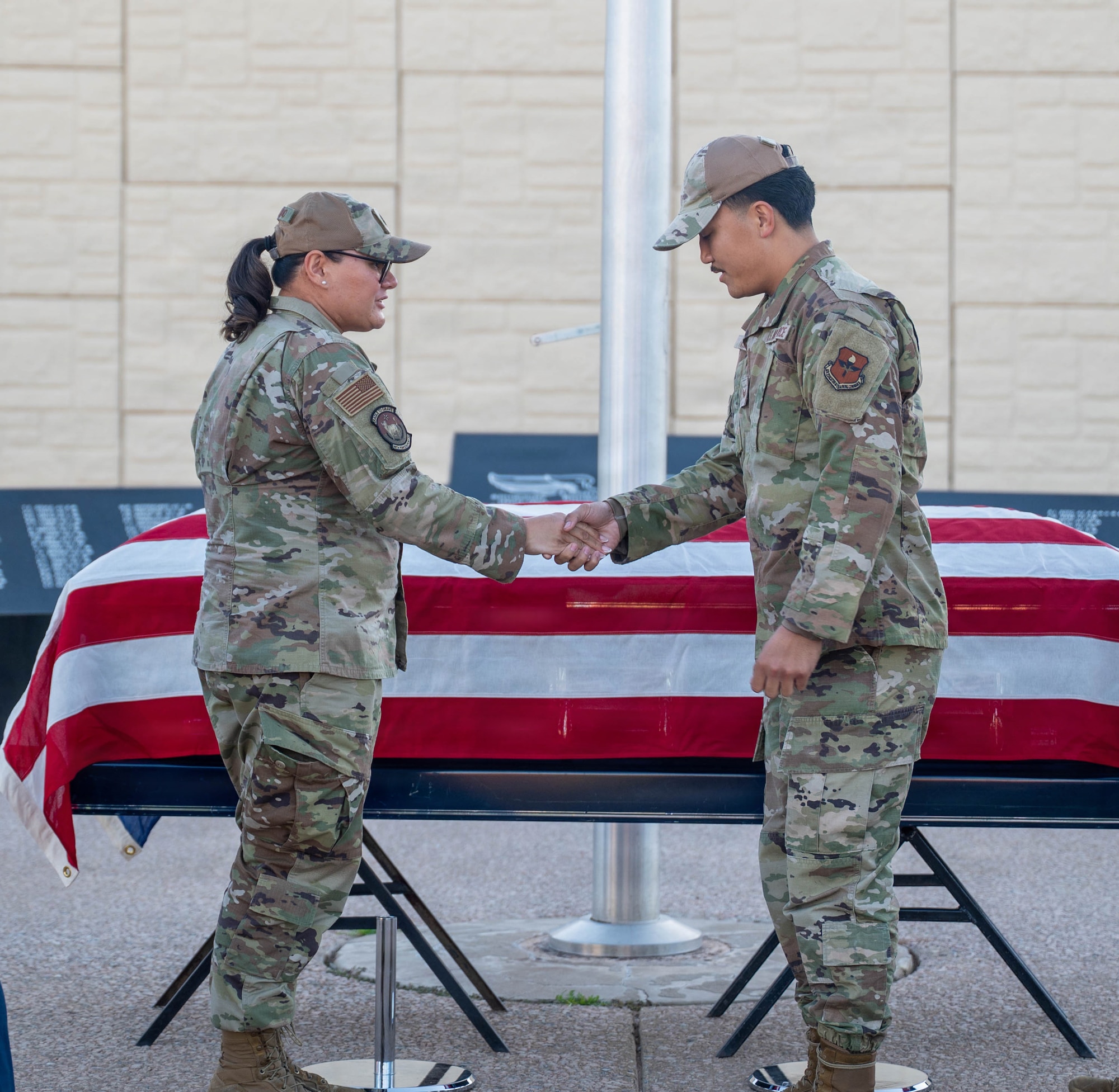 U.S. Air Force Lt. Col. Maria Berardo (left), 56th Force Support Squadron commander, shakes hands with Senior Airman Matthew Lucero (right), 56th Fighter Wing honor guardsman, after presenting a challenge coin for exceptional performance during a ceremony, Dec. 2, 2025, at Luke Air Force Base, Arizona.
