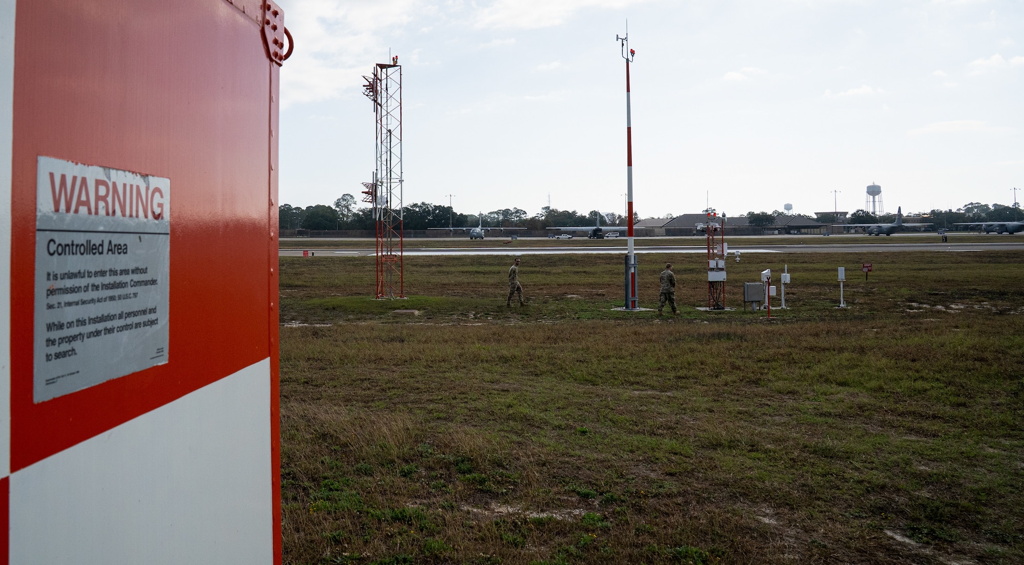Two servicemen in OCPs walking out to an airfield.