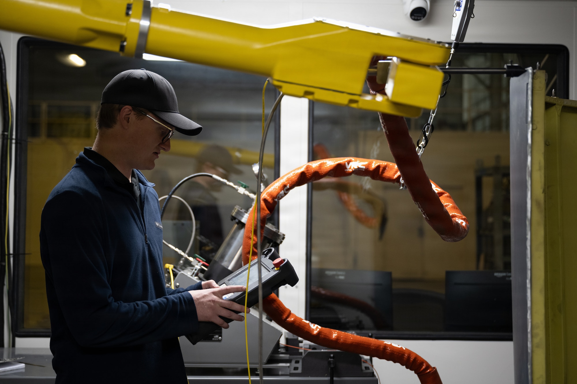 An engineer uses a remote to control a cold spray robot.