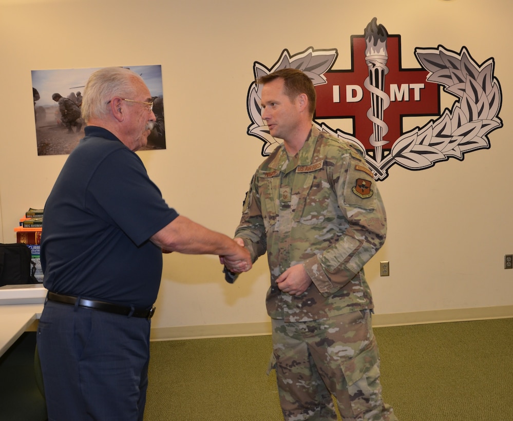 Former Air Force Independent Duty Medical Technician, retired Senior Master Sgt. Michael Currey, is presented the IDMT badge from Senior Master Sgt. Zachary Pingree, IDMT course senior enlisted leader, as a token of thanks for his visit. Currey answered questions and sharing stories about his experiences from decades ago with IDMT course instructors and students November 20 at the Medical Education and Training Campus on Joint Base San Antonio-Fort Sam Houston, Texas.