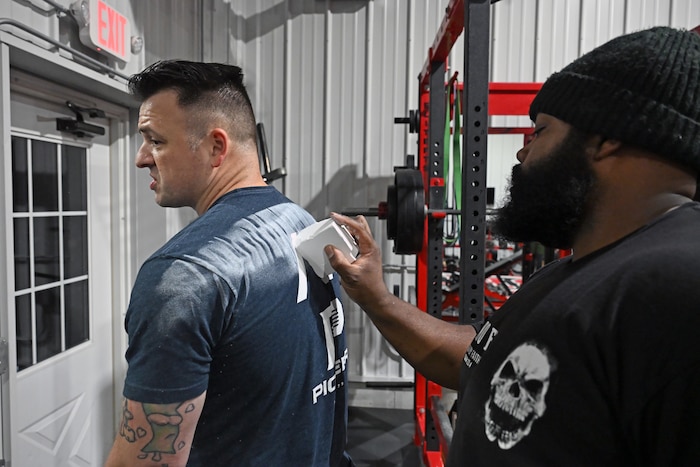 Justin Robinson, right, chalks Tech. Sgt. Zackary George’s back here, Oct. 28. George recently won first place in USA Power Lifting’s Masters 1 Division and fifth place in its Raw Open with a combined total lift of 1,407.6 pounds. George is a program manager for Kessel Run’s Patriot Excalibur. Kessel Run is part of the Department of the Air Force’s Program Executive Office for Command, Control, Communications and Battle Management. Kessel Run is a division that delivers resilient command and control and targeting software capabilities that provide warfighters with decision advantage. (Official Air Force Photo by Richard Blumenstein)