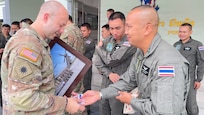 Capt. Taylor Payne, Army Aviation Support Facility 2 commander and State Partnership Program aviation liaison, receives a coin from his Royal Thai Army counterpart during the closing ceremonies following an Aviation Subject Matter Expert Exchange in Lop Buri, Thailand, Dec. 12, 2025.