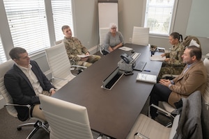 Group of people gather at a table having a meeting.