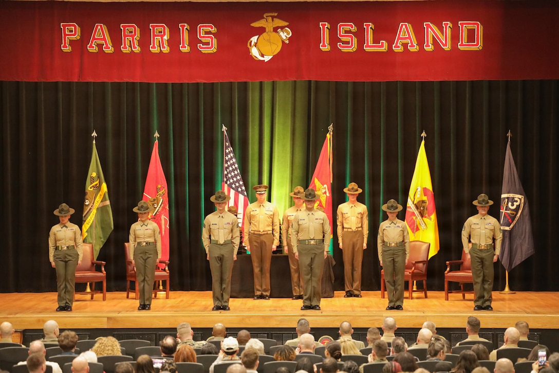 U.S. Marines stand on stage in front of an audience during the graduation of Drill Instructor School class 1-26 on Marine Corps Parris Island, S.C., Dec. 17, 2025. To become a drill instructor, qualified Marines must first attend and graduate from Drill Instructor School, an 11-week course designed to develop their leadership and abilities so they can successfully perform the duties of a drill instructor. (U.S. Marine Corps photo by Cpl. Jacob Richardson)