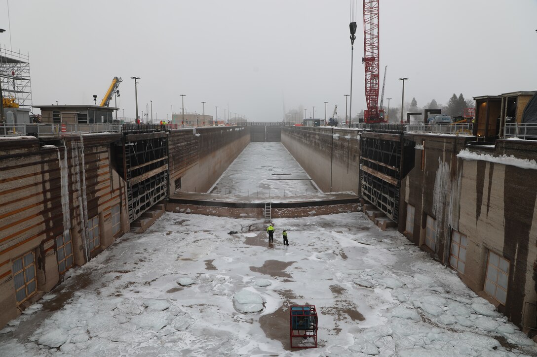 The dewatered Poe Lock in Sault Ste. Marie, Michigan sits mostly empty besides a thick layer of ice on the floor and two Soo Locks' workers inspecting the floor of the lock.
