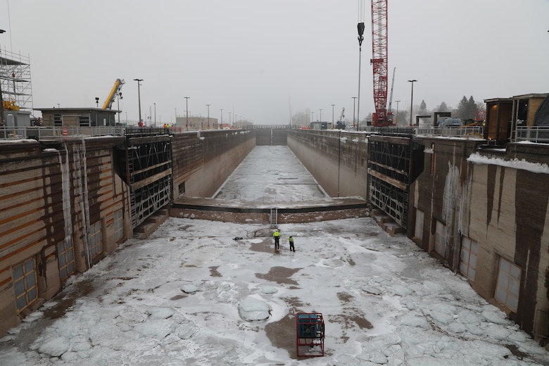 The dewatered Poe Lock in Sault Ste. Marie, Michigan sits mostly empty besides a thick layer of ice on the floor and two Soo Locks' workers inspecting the floor of the lock.