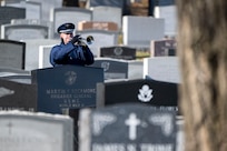 Trumpeter performs in the cemetery surrounded by tombstones.