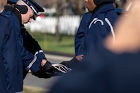 Airmen fold a flag together with tombstones in the background.
