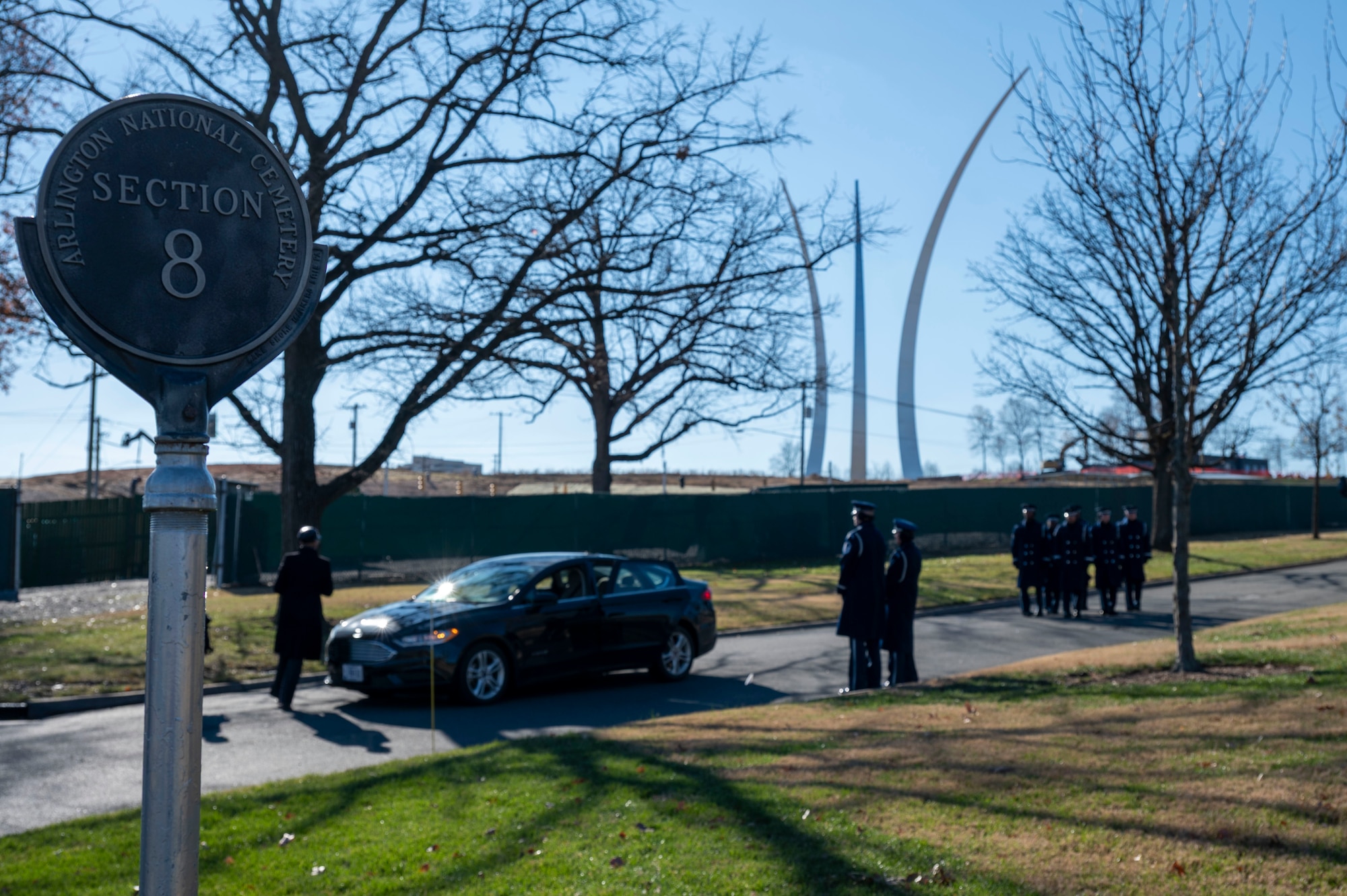 Honor Guardsmen stand at ease with the Air Force Memorial in the background.