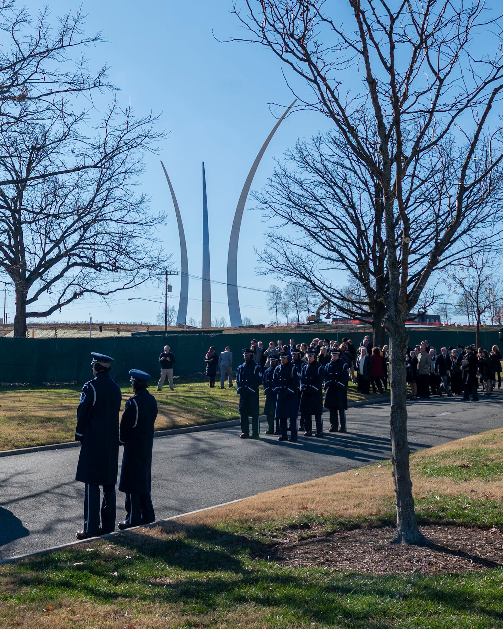 Honor Guardsmen stand at ceremonial at-ease with the Air Force Memorial in the background.