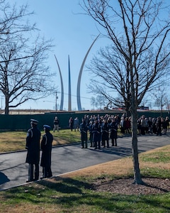 Honor Guardsmen stand at ceremonial at-ease with the Air Force Memorial in the background.