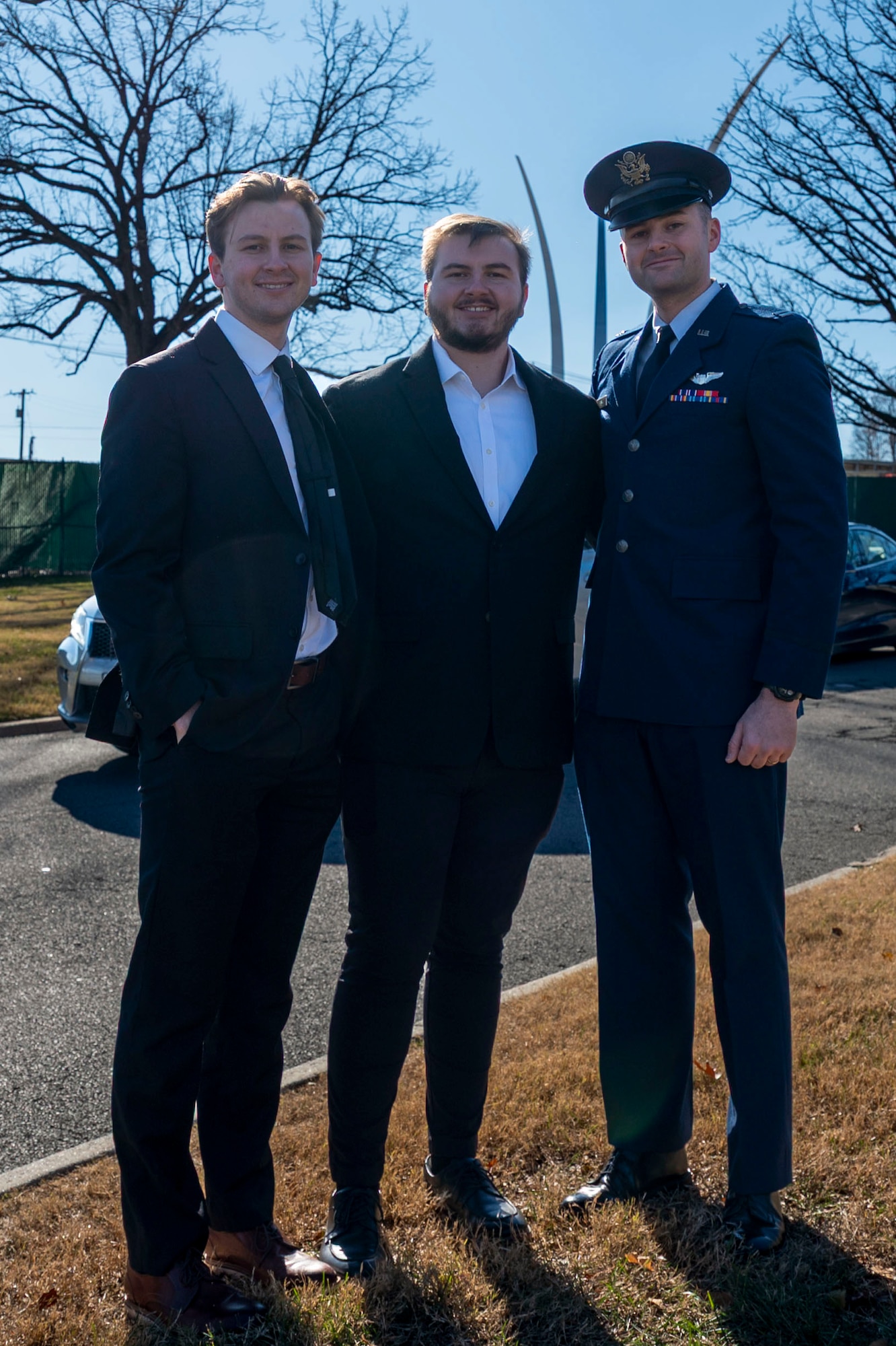 Three men stand in Arlington Cemetery, one in an Air Force dress uniform.
