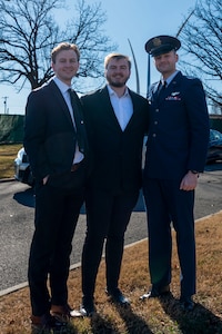 Three men stand in Arlington Cemetery, one in an Air Force dress uniform.