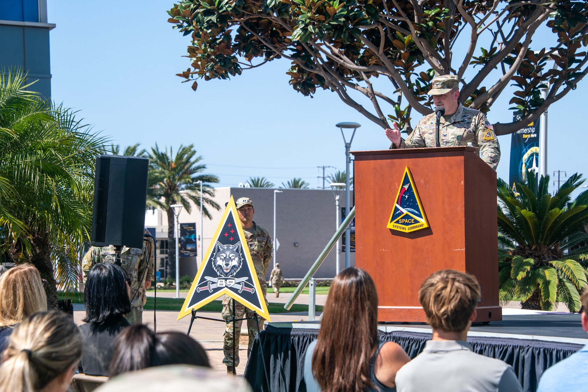 USSF Col. Brendan Hochstein, commander of Space Systems Command’s (SSC) System Delta (SYD 89), knife hands the audience while giving his closing remarks at Los Angeles Air Force Base on September 30, 2025. SYD 89 develops and delivers cyber, ground- and space-based combat power capabilities to contest and control the space domain through fires, movement, and maneuver, preserving U.S., Allied, and commercial freedom of action in, from, and to space. SYD 89 supports the Space Combat Power (SCP) Program Executive Office (PEO). (U.S. Space Force photo by Van Ha)