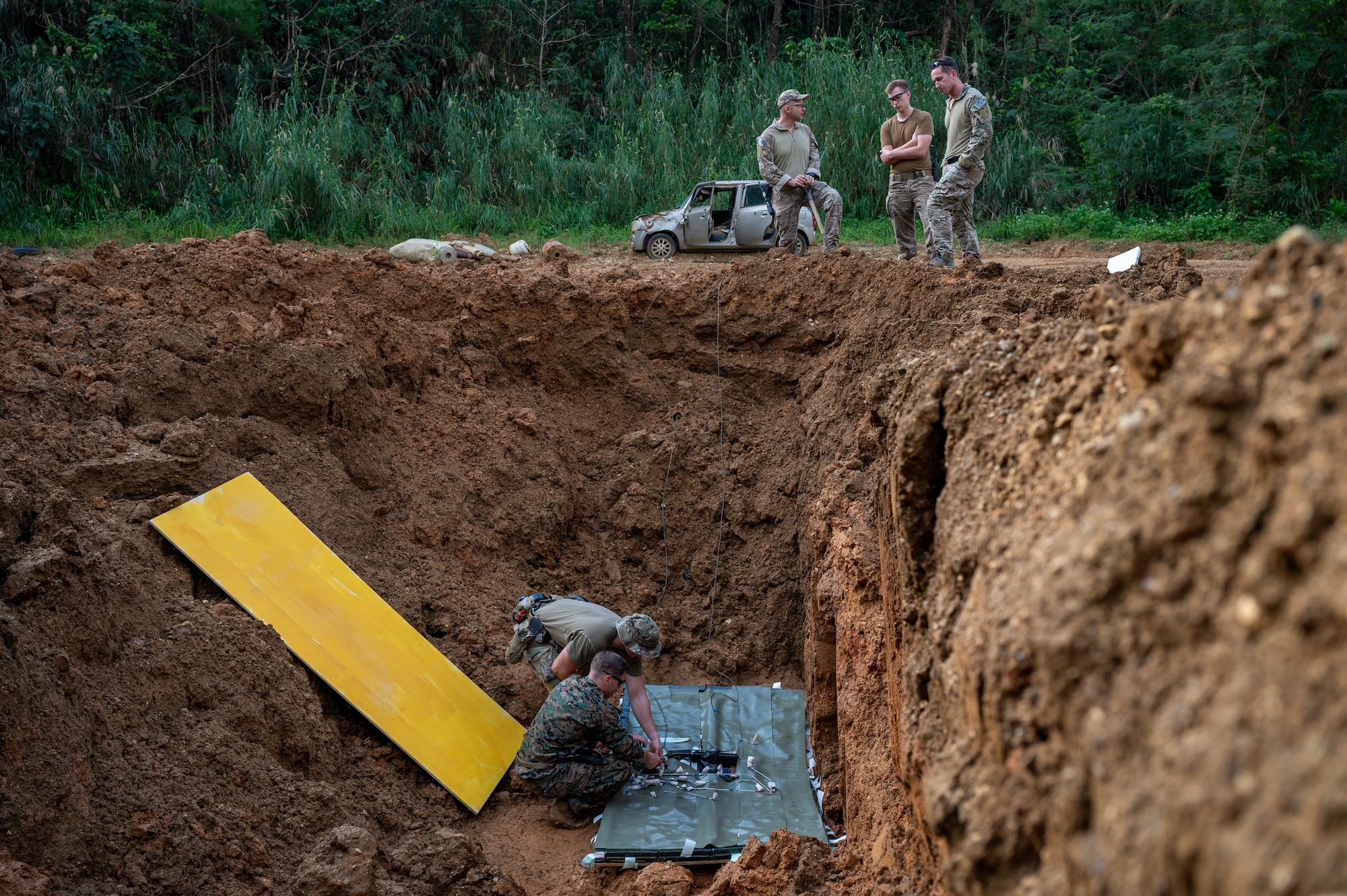 U.S. Air Force members from the 18th Civil Engineer Squadron and a U.S. Marine from the 3D Intelligence Battalion conduct final safety checks prior to a controlled detonation at Kadena Air Base, Japan, Dec. 18, 2025. The controlled detonation reinforces the 18th Wing’s commitment to maintaining a safe operating environment while ensuring forces remain ready to respond at a moment’s notice. (U.S. Air Force photo by Airman 1st Class Francisco Huerta)