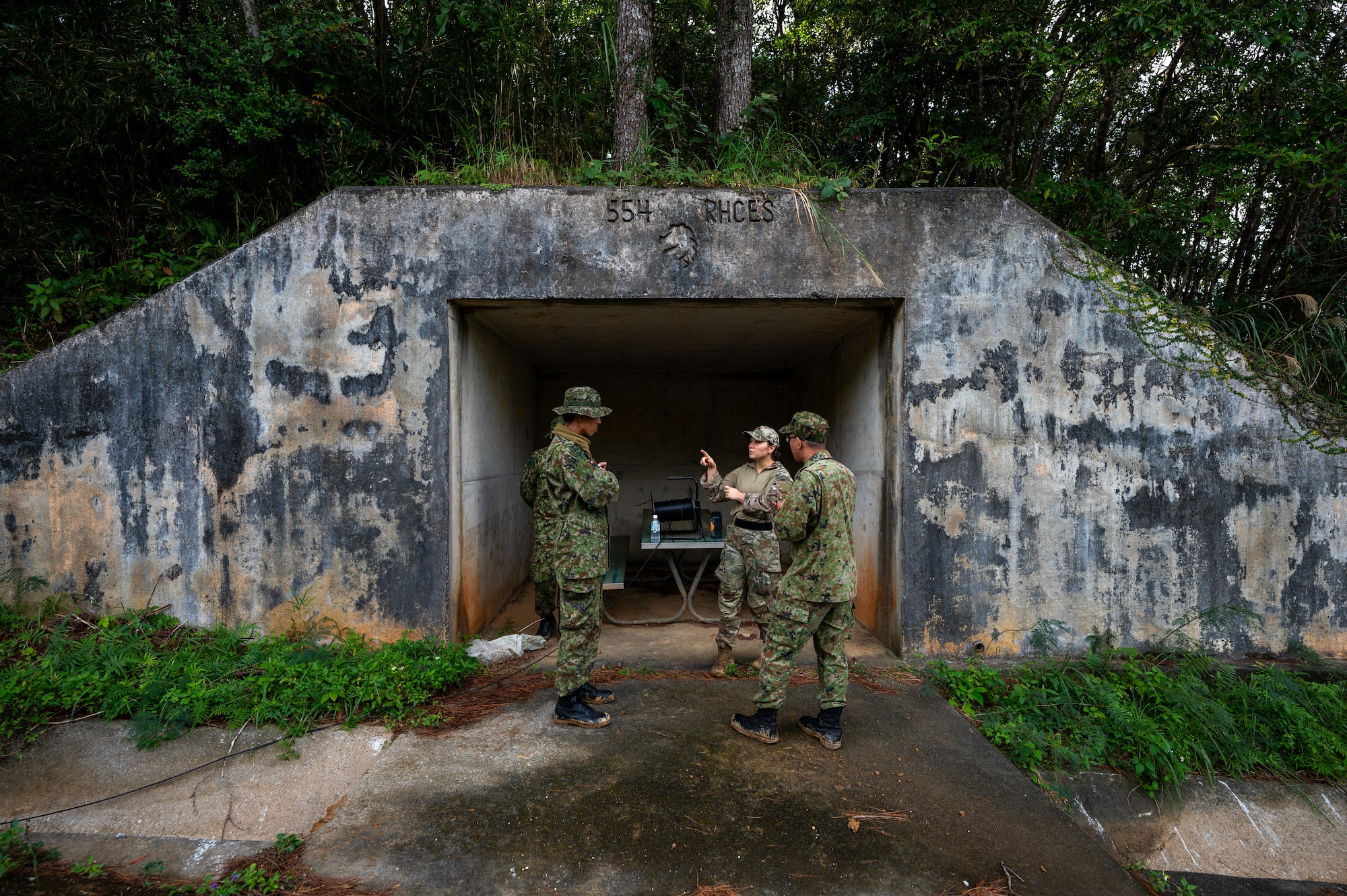 U.S. Air Force Capt. Brittany Dragan, center, 18th Civil Engineer Squadron explosive ordnance disposal flight commander, briefs members from the Japan Ground Self-Defense Force 101st EOD unit at Kadena Air Base, Japan, Dec. 18, 2025. Readiness-focused controlled detonations like this enable Kadena to remain a cornerstone of stability and deterrence in the Indo-Pacific. (U.S. Air Force photo by Airman 1st Class Francisco Huerta)